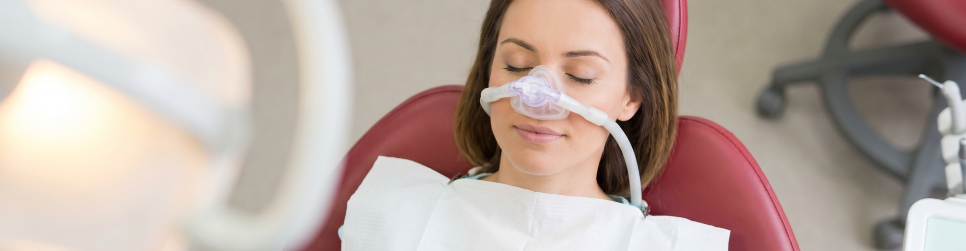 Patient wearing a nasal sedation mask while relaxing in a dental chair before or during a dental procedure.